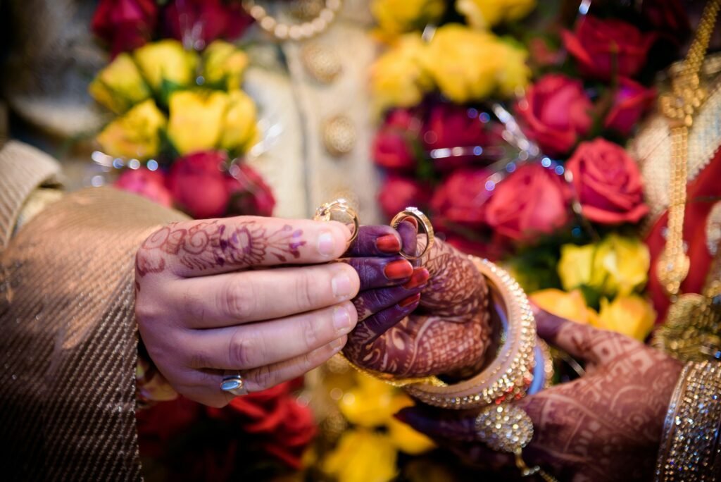 Shallow focus of an Indian couple with Mehndi on their hands holding wedding rings